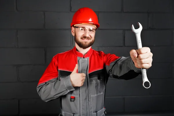 Mann trägt Overall mit rotem Helm und Schraubenschlüssel — Stockfoto