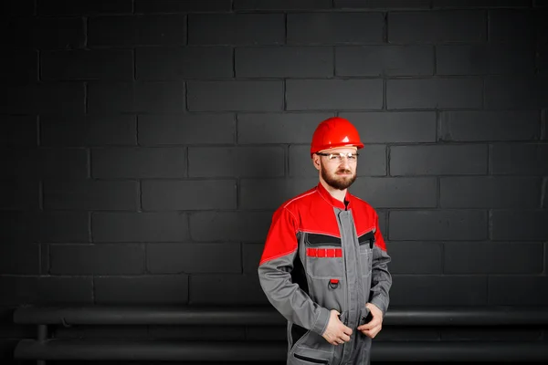 Porträt eines lächelnden Mannes in Overalls in der Nähe von Ziegelmauer und Auge — Stockfoto