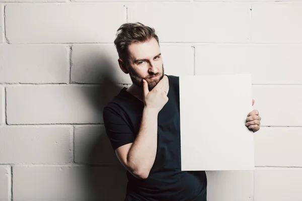 Uomo con barba che mostra carta bianca vuota — Foto Stock