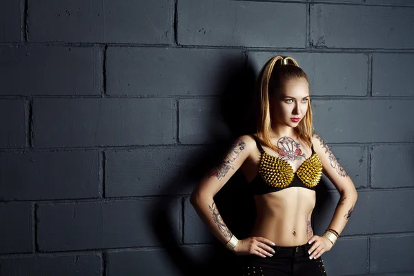 Девушка в стиле рок с татуировкой рядом с кирпичной стеной — стоковое фото