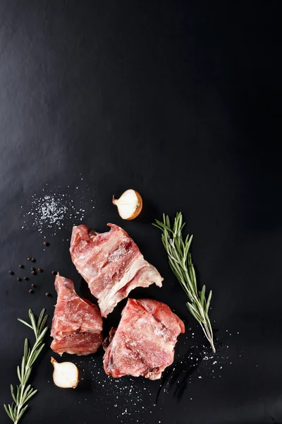 Tranches de viande congelée au romarin et oignon sur papier noir — Photo