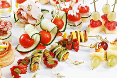 Close-up view set of canapes with vegetables, salami, seafood, meat and decoration on whie plate studio isolated isolated with space for text template