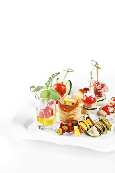 Close-up view set of canapes with vegetables, salami, seafood, meat and decoration on whie plate studio isolated — 스톡 사진