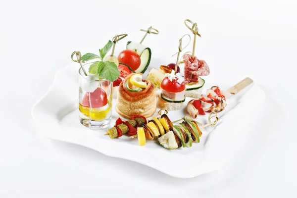 Close-up view set of canapes with vegetables, salami, seafood, meat and decoration on whie plate studio isolated — ストック写真