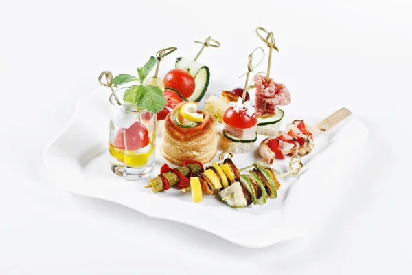 Close-up view set of canapes with vegetables, salami, seafood, meat and decoration on whie plate studio isolated — Φωτογραφία Αρχείου