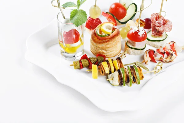 Vue rapprochée ensemble de canapés avec légumes, salami, fruits de mer, viande et décoration sur plaque de whie studio isolé — Photo