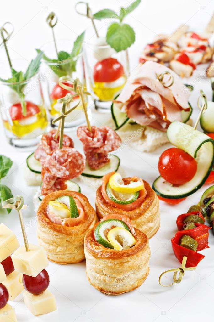 Close-up view set of canapes with vegetables, salami, seafood, meat and decoration on whie plate studio isolated