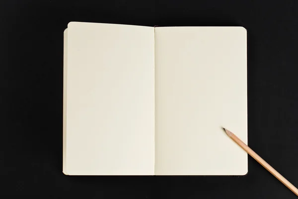 Abra o bloco de notas em branco com páginas vazias com um lápis sobre fundo preto — Fotografia de Stock