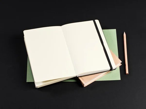 Open blank notepad with empty white pages laying above book with — Stok fotoğraf