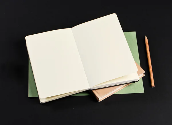 Open blank notepad with empty white pages laying above book with — ストック写真