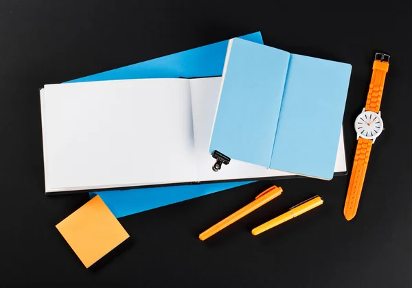 Student girl workplace. open notepads with blue and white pages. Orange stickers and orange pens with orange watches — Stok fotoğraf