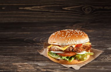 ızgara et, peynir, domates, Kraft kağıt ahşap yüzeyi tarih ile lezzetli peynirli burger. Fast food şablonu.