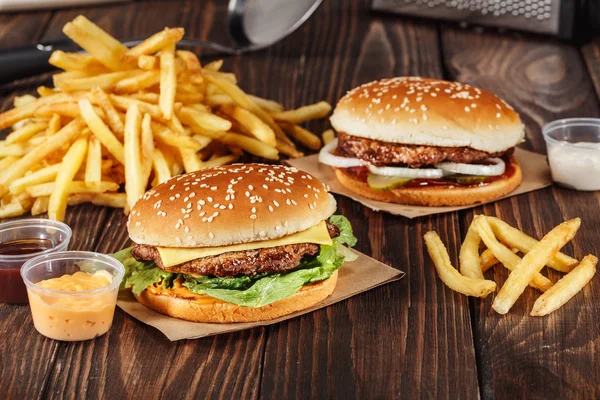 Patates kızartması Kraft kağıt mutfak ahşap yüzeyi tarih ile ızgara et ile iki hamburger. Fast food şablonu. gerçek fotoğraf — Stok fotoğraf