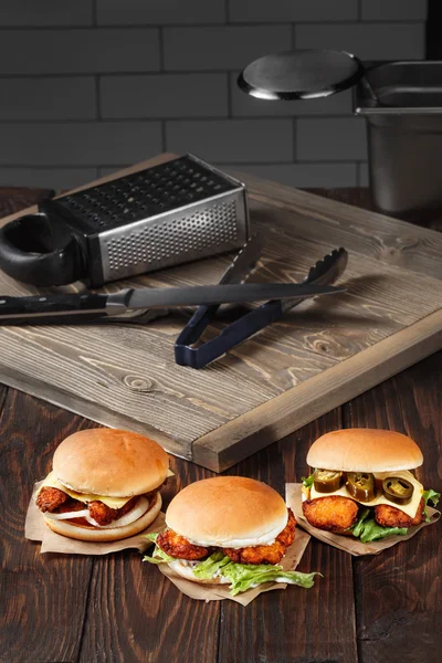 Jogo de três hambúrgueres de frango saborosos na superfície de madeira na cozinha. modelo de fast food. alimentos não saudáveis . — Fotografia de Stock