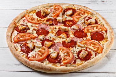Delicious fresh pizza with chicken ham tomato served on wooden t
