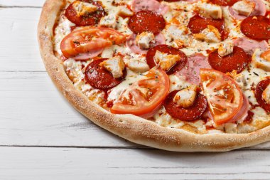Delicious fresh pizza with chicken ham tomato served on wooden t