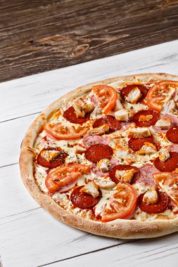 Delicious fresh pizza with chicken ham tomato served on wooden t