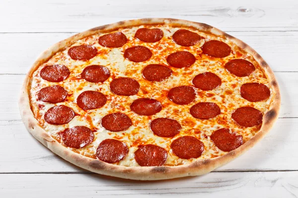 Läckra färsk salami pizza serveras på träbord — Stockfoto