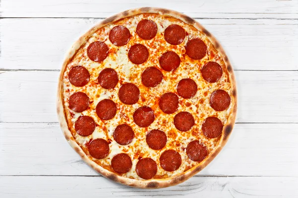 Delicious fresh salami pizza served on wooden table. Top view. — Stock Photo, Image