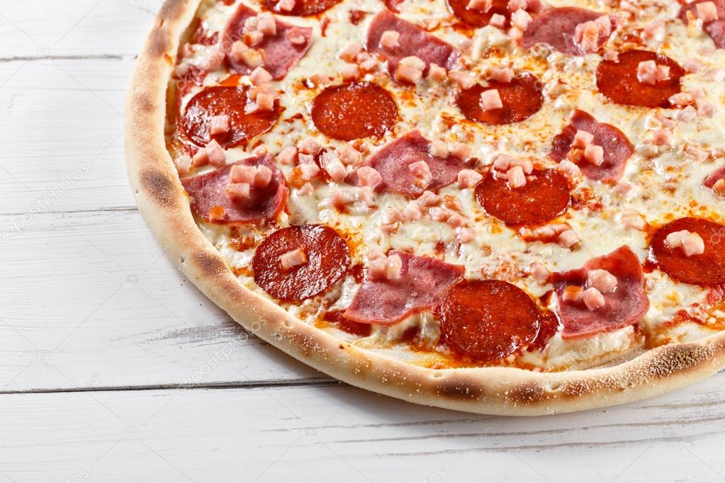 Delicious fresh pizza with sausage ham salami served on wooden t