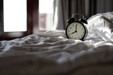 Sabahları yatak odasında klasik alarmlı saat ve pencerelerde güneş ışığı. Kışın ya da sonbahar mevsiminde uyumak.