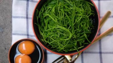 Taze çiğ yumurta ve omlet veya bol yağda kızartılmış cha-om yaprakları için Cha-om yaprağı. Popüler bir Tayland yemeği. Yavaş çekim.
