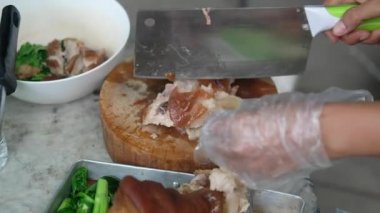 Taylandlı tüccar bıçak kullanıyor. Haşlanmış domuz budu, tahta bacağı satıyor. Tayland yemeği.