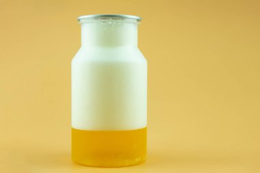 Sarı arka planda köpüklü bir bardak taze bira. Kapat.