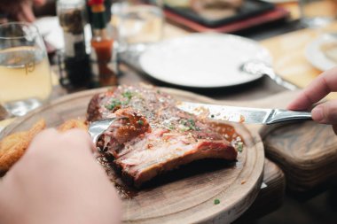 Adam ızgara domuz pirzolası yerken çatal ve bıçak kullanıyor. Kapat.