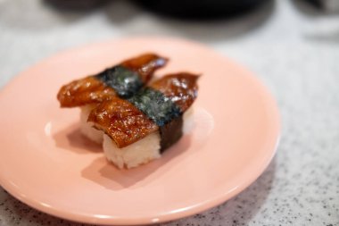 Pembe tabakta yılan balıklı Nigiri sushi.