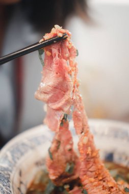 Tayland erişte kasesindeki çubukları kullanarak Wagyu bifteğinden bir dilim aşırmak. Seçici odak