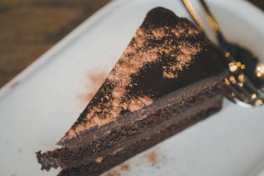 Çikolata tozuyla süslenmiş beyaz tabakta çikolatalı pastanın üç dilimini kapat.