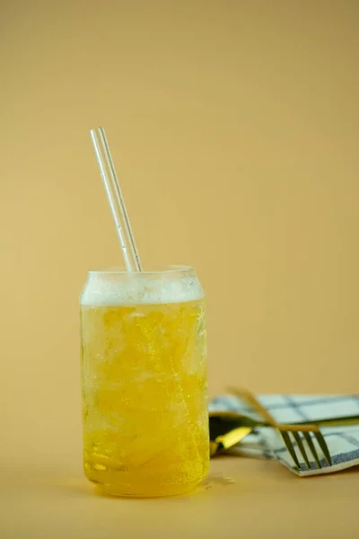 黄色の背景に氷と藁と軽ビールのガラス — ストック写真