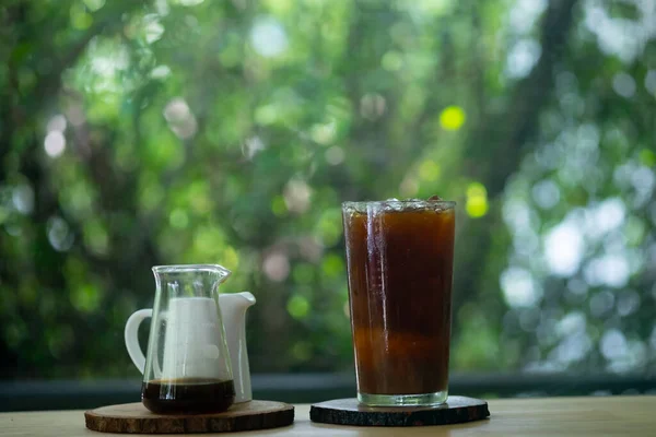 Glass of iced black coffee on wood table in cafe