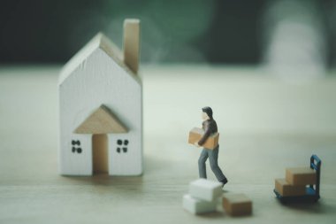 Minyatür işçi o şeyi minyatür eve taşıyor. Gayrimenkul ve emlak işi kavramı ve yeni eve taşınma hizmeti