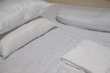 Kapalı beyaz çarşaf ve beyaz havluyla yastık. Yeni yatak kavramı