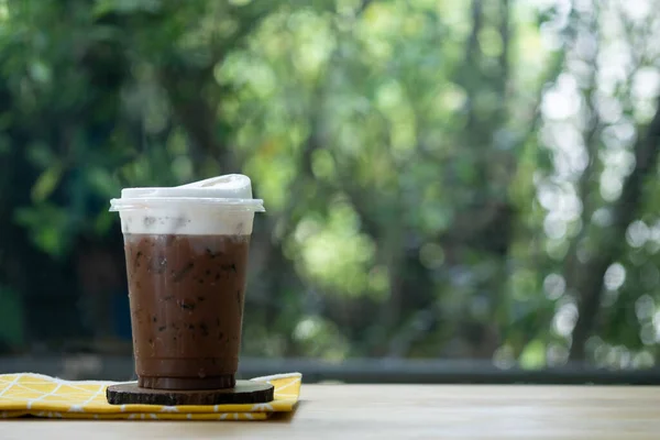 Iced mocha in plastic cup on wooden table. Coffee beverage in coffee house