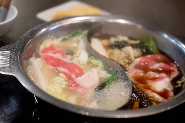 2つのスープのために特別に作られた鍋で2つのスープの好意で豚肉と牛肉を沸かす — ストック写真