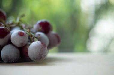 Tahta masada soğumuş çekirdeksiz bir üzüm kümesi. Sığ alan derinliği ve seçici odak ile kapat, boşluğu kopyala