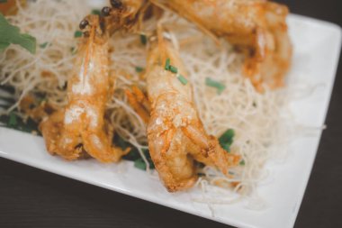 Beyaz tabakta sarımsaklı ve biberli kızarmış karides.