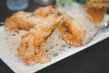 Beyaz tabakta sarımsaklı ve biberli kızarmış karides.