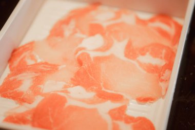 Beyaz tepside ince domuz dilimleri. Kapat.