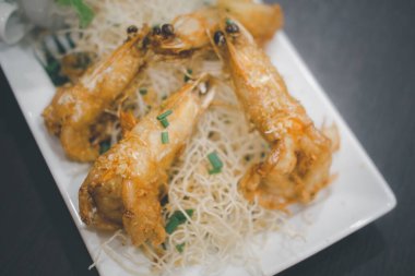 Beyaz tabakta sarımsaklı ve biberli kızarmış karides.