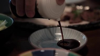 Geleneksel Japon yemekleri olan sashimi ya da nigiri daldırmak için küçük tabağa el yapımı soya sosu ya da Shoyu Grom siyah çömleği dök. Yaşam tarzı geleneksel yemek yemek.