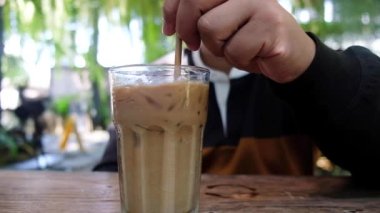 Kafede buzlu kahveyi karıştıran bir adam.