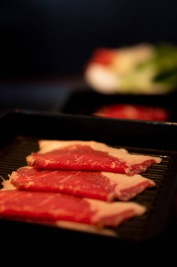 Yakiniku için siyah tepside servis edilen çiğ eti kapat..
