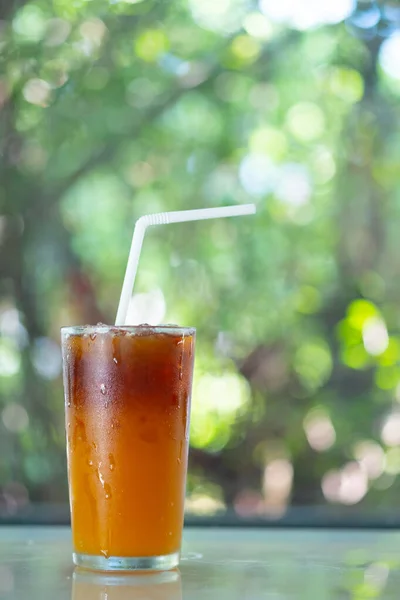 Iced black coffee mixed with fresh orange juice arrange on a nature background.