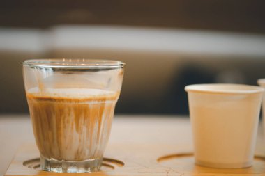 Kirli kahve, buzlu sütten yapılma. Bardaki ahşap kafede bir fincana eklenmiş espresso.