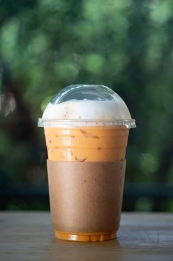 Tahta masada kahverengi kağıt kollu soğuk Thai sütlü çay.