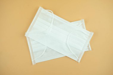 Sarı arka planda tıbbi maske ya da cerrahi kulak ilmeği maskesi